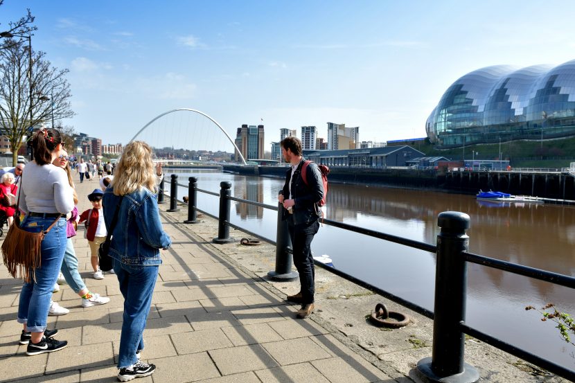 Tour guide stood in front of small group of people alongside the river