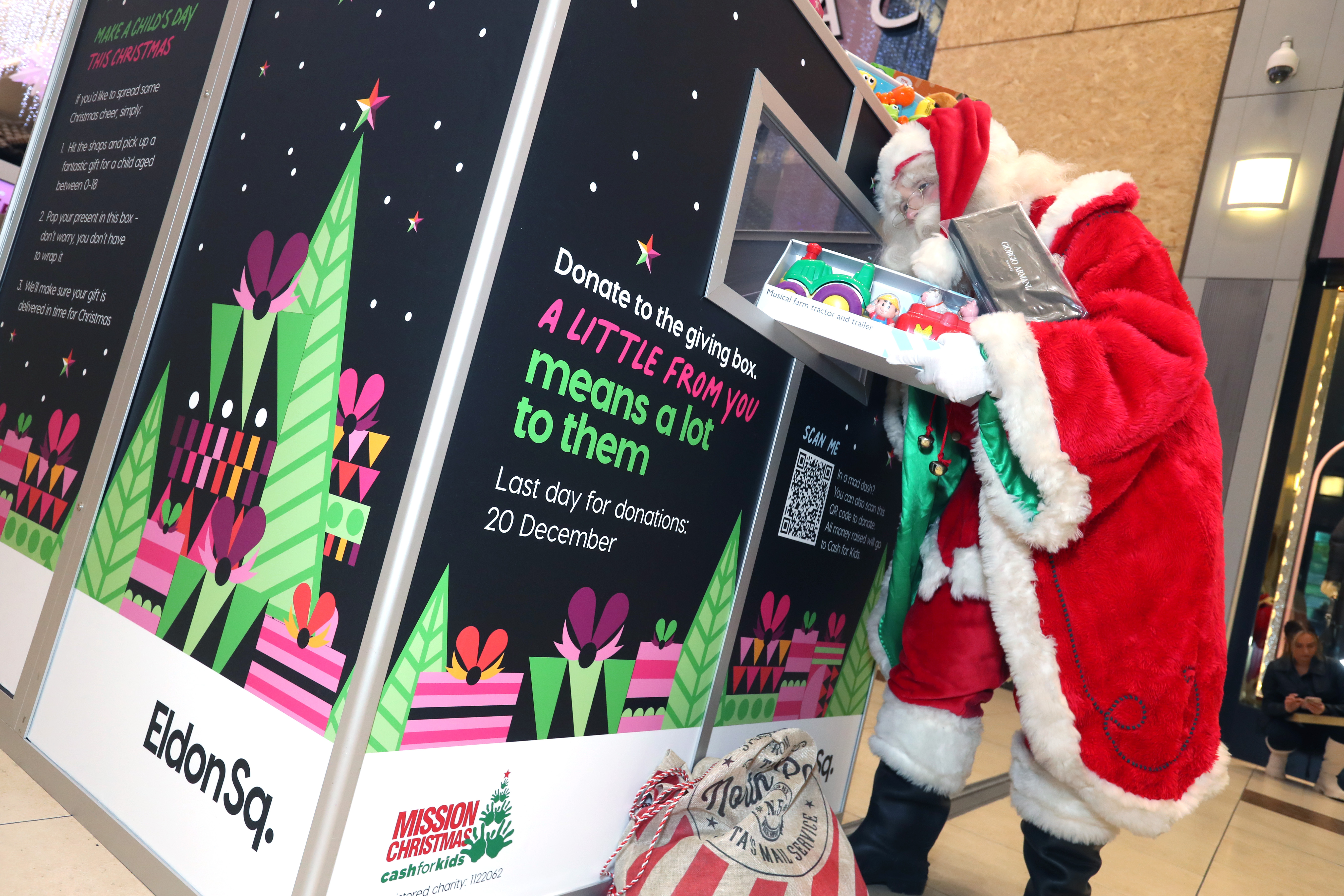 Person dressed as Santa Claus putting gifts in a large box in Eldon Square centre