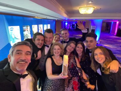 Selfie-style image, lots of Ryder Architecture team members smiling at camera, one holding award. They are all dressed in black-tie.