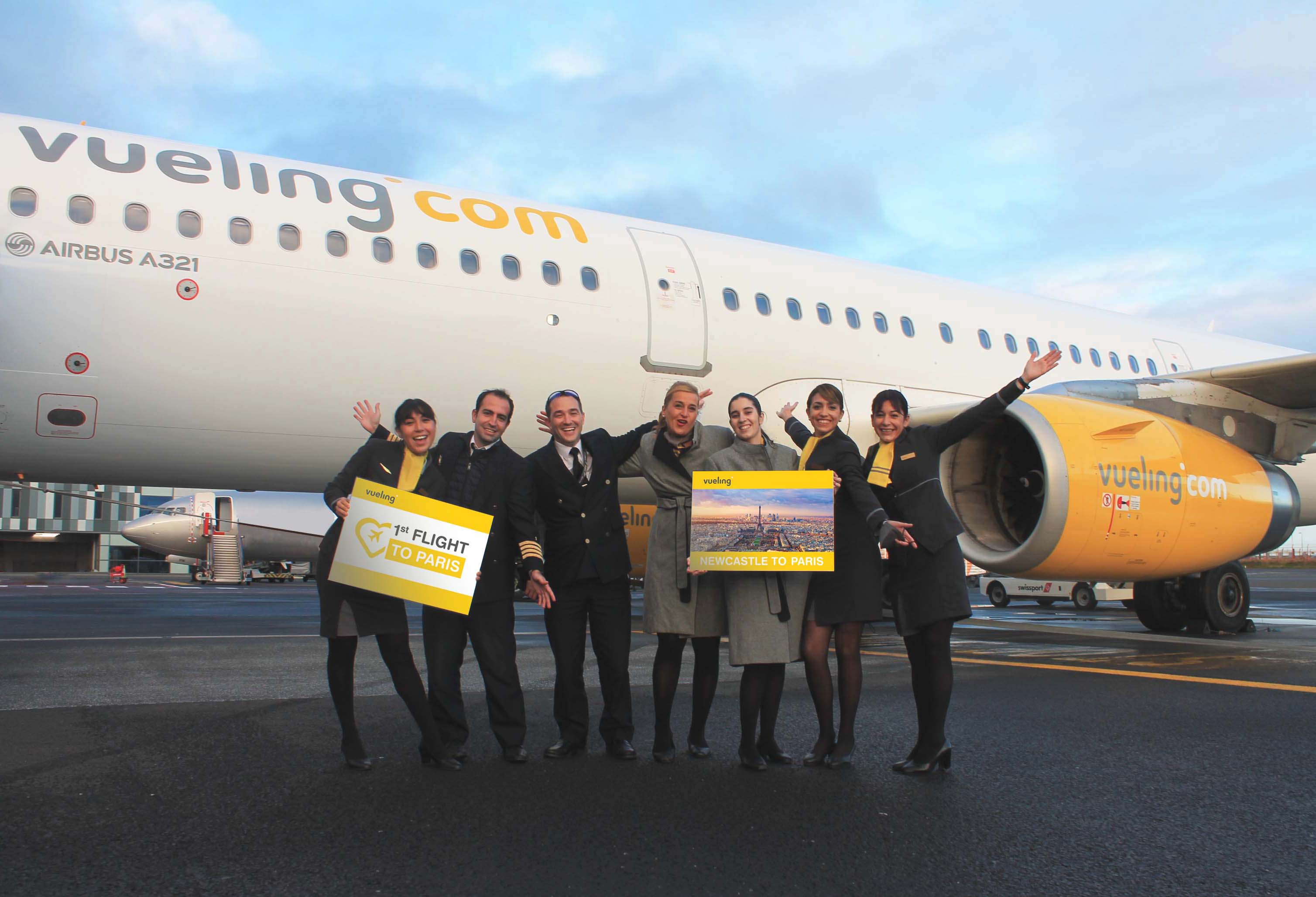 Airline staff pose in front of white and yellow Veuling plane