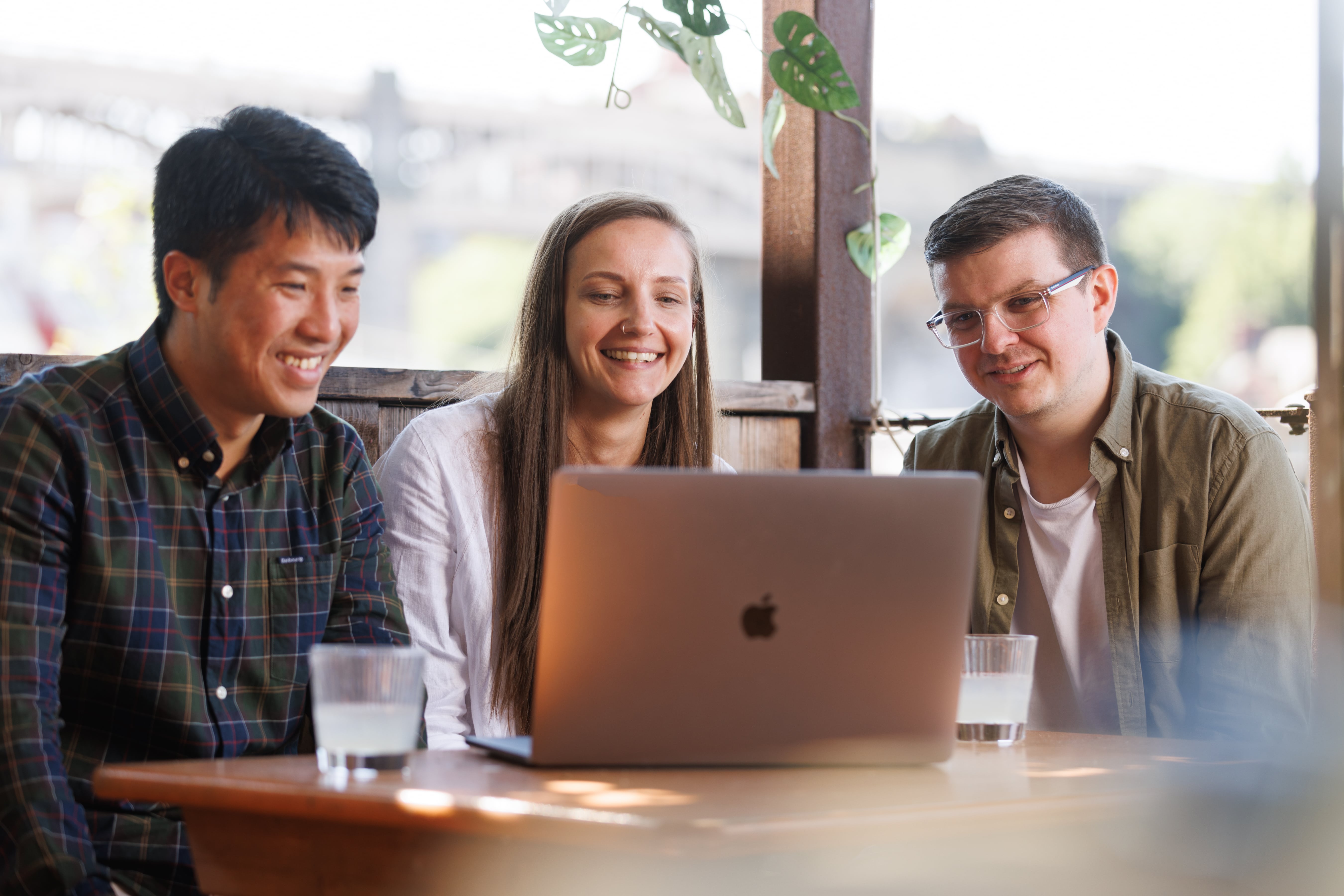 Three young people sat around laptop screen