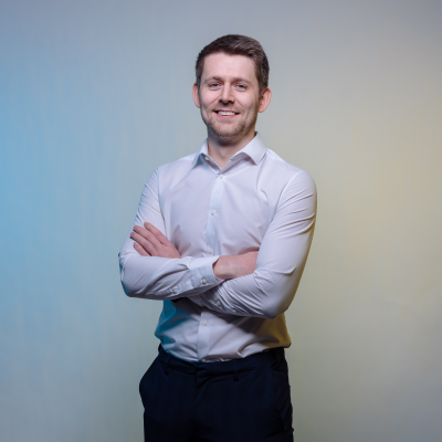 David stood in studio with blank background for headshot with his arms crossed.