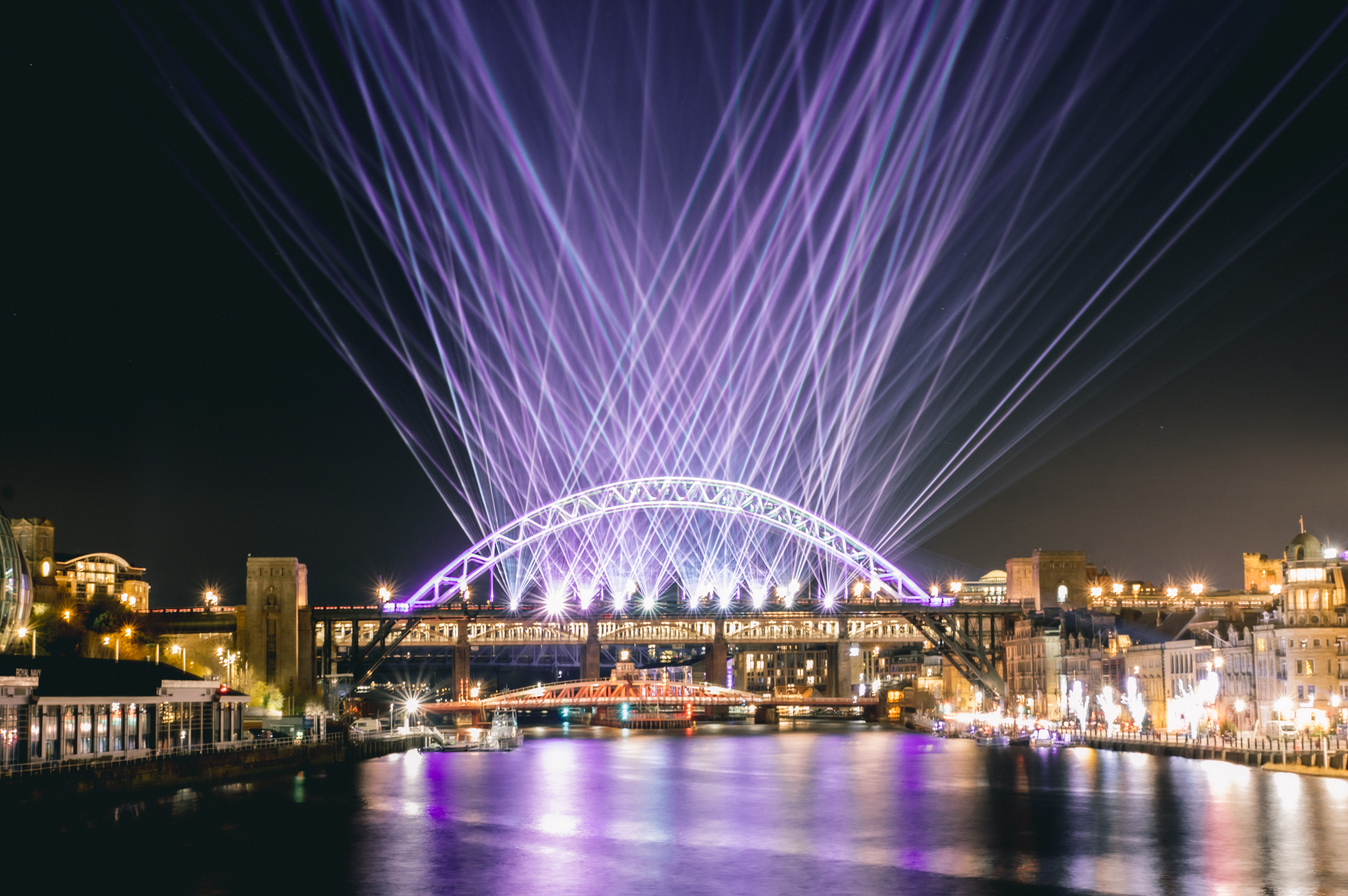 Image of River Tyne at nighttime with laser beams protruding from the Tyne Bridge.
