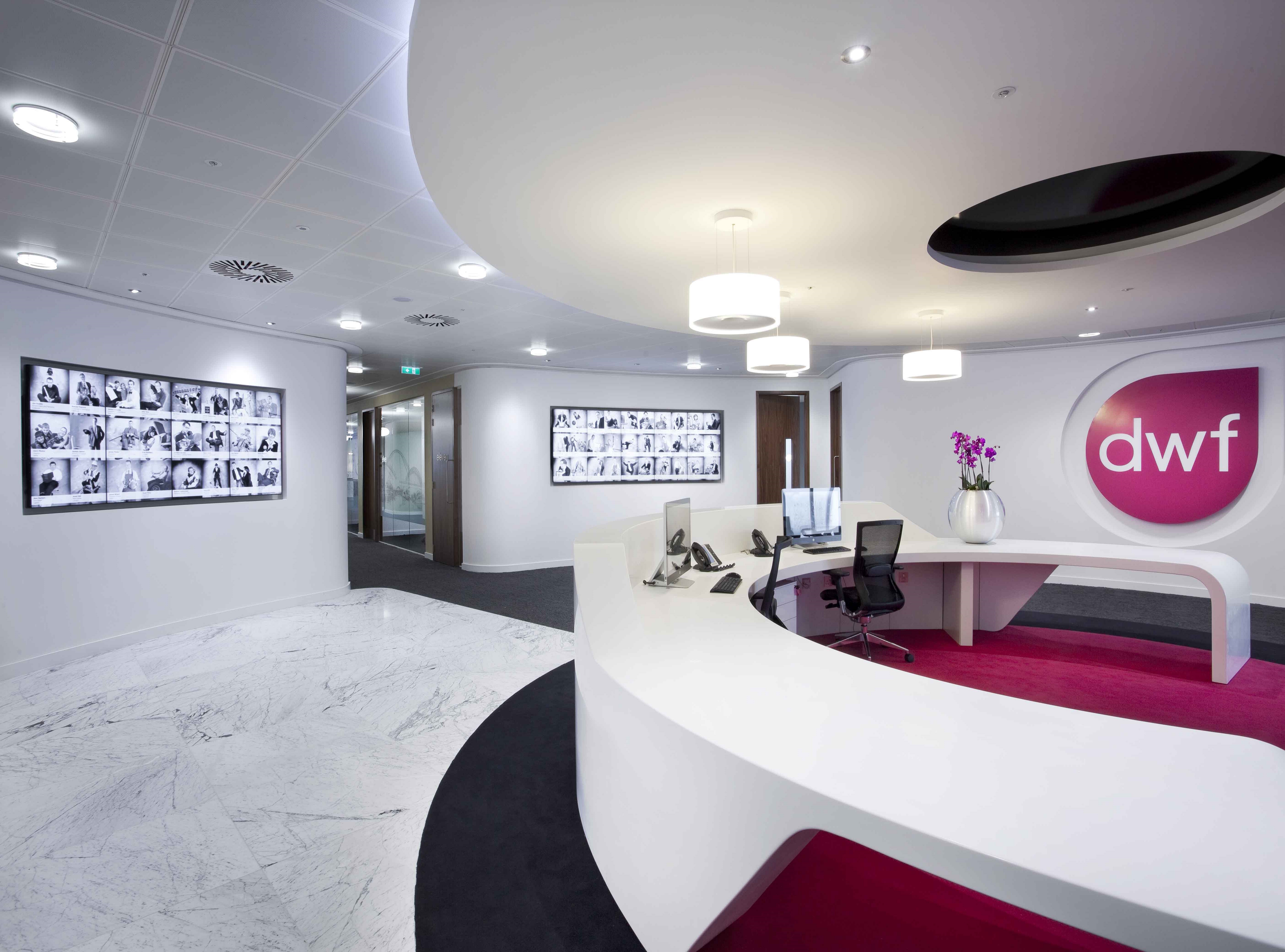 Image of interior of DWF office. Lots of white curved desks and pink DWF logo on the wall.