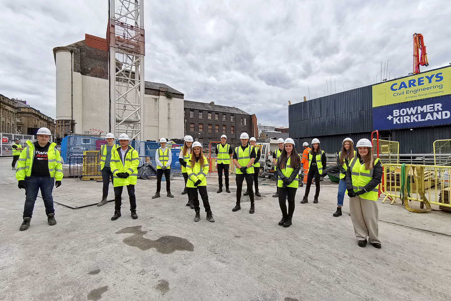 About a dozen of the PlanBEE cohort on a building site stood in hi-vis and hard hats
