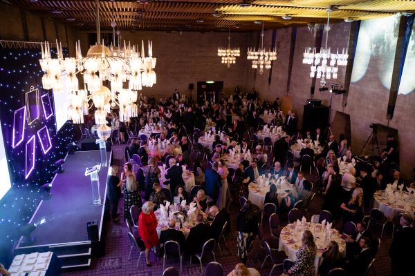 Birds eye view of the North east England Tourism Awards ceremony from 2023 with guests seated at round dinner tables in the Newcastle Civic Centre in front of purple-lit stage