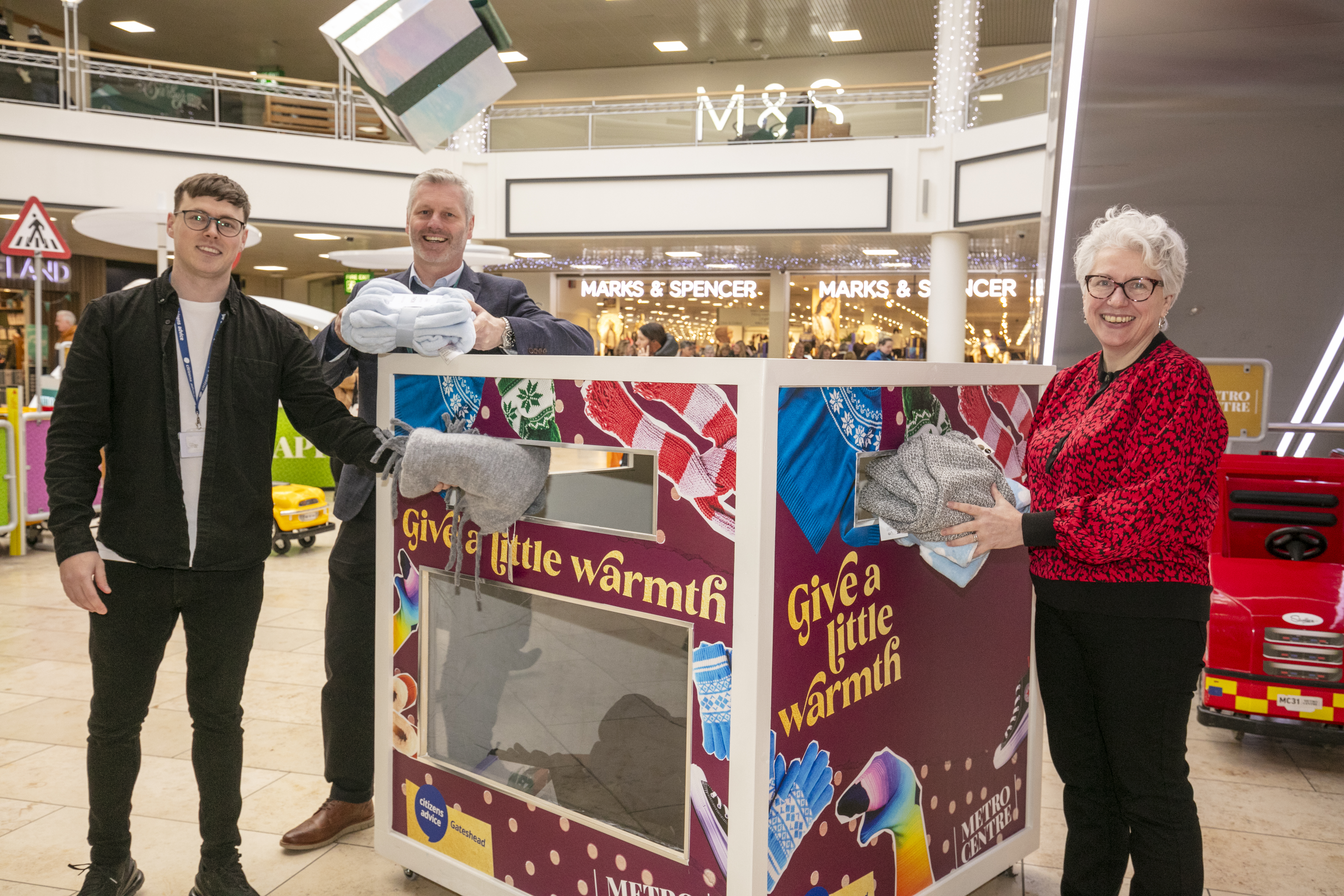 Michael, Gavin & Judith standing smiling at the camera as they donate to the Winter Warmer Appeal.
