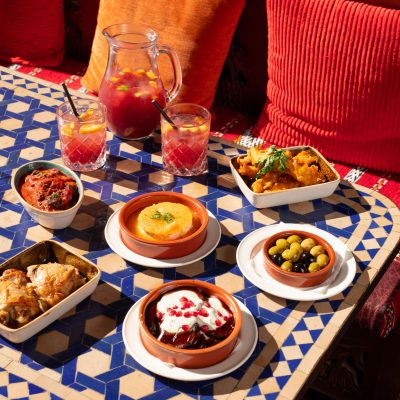 Lots of small plates of food on a blue and white tiled table