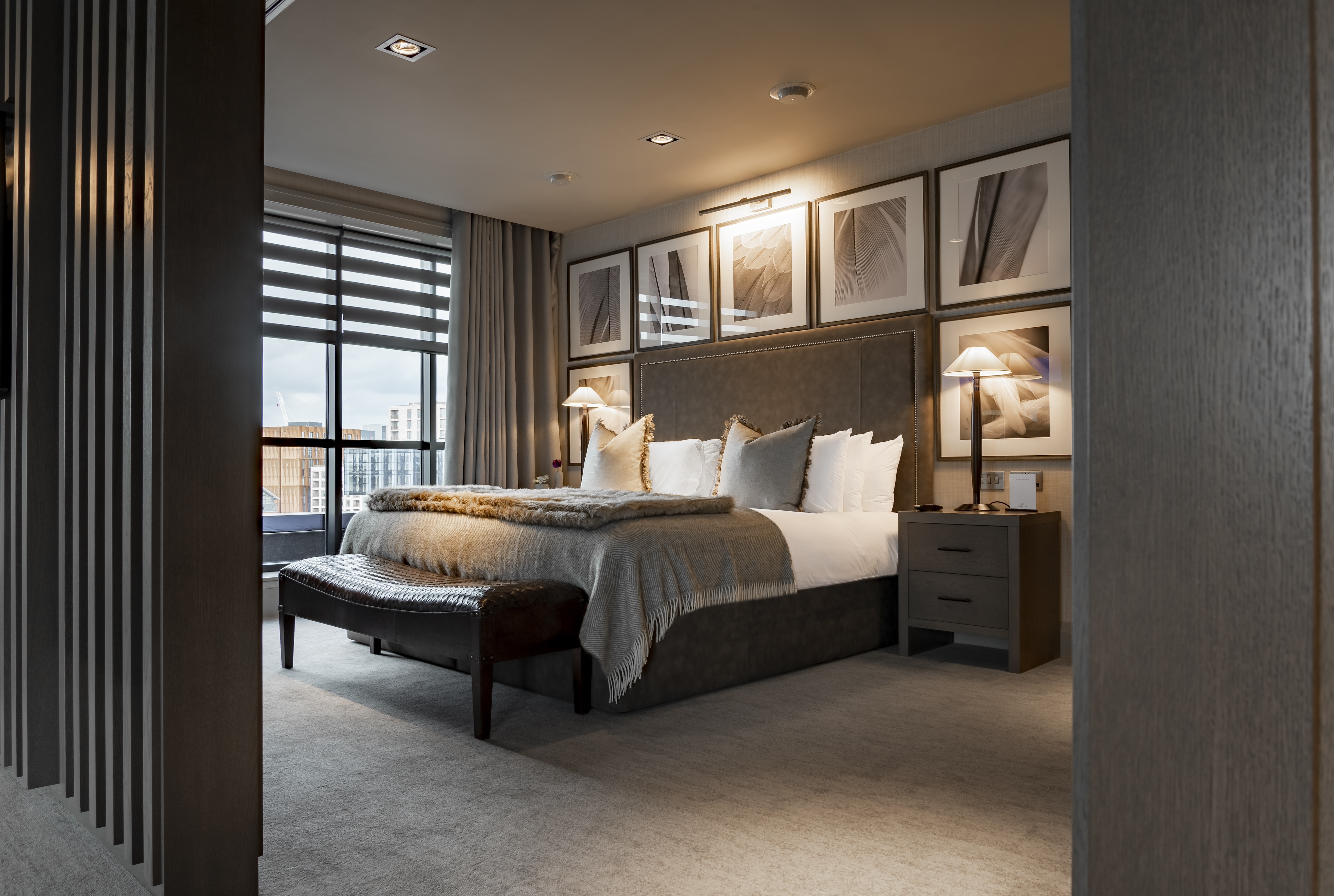 Image of grey and white themed hotel bedroom with large bed framed by large square photo frames.