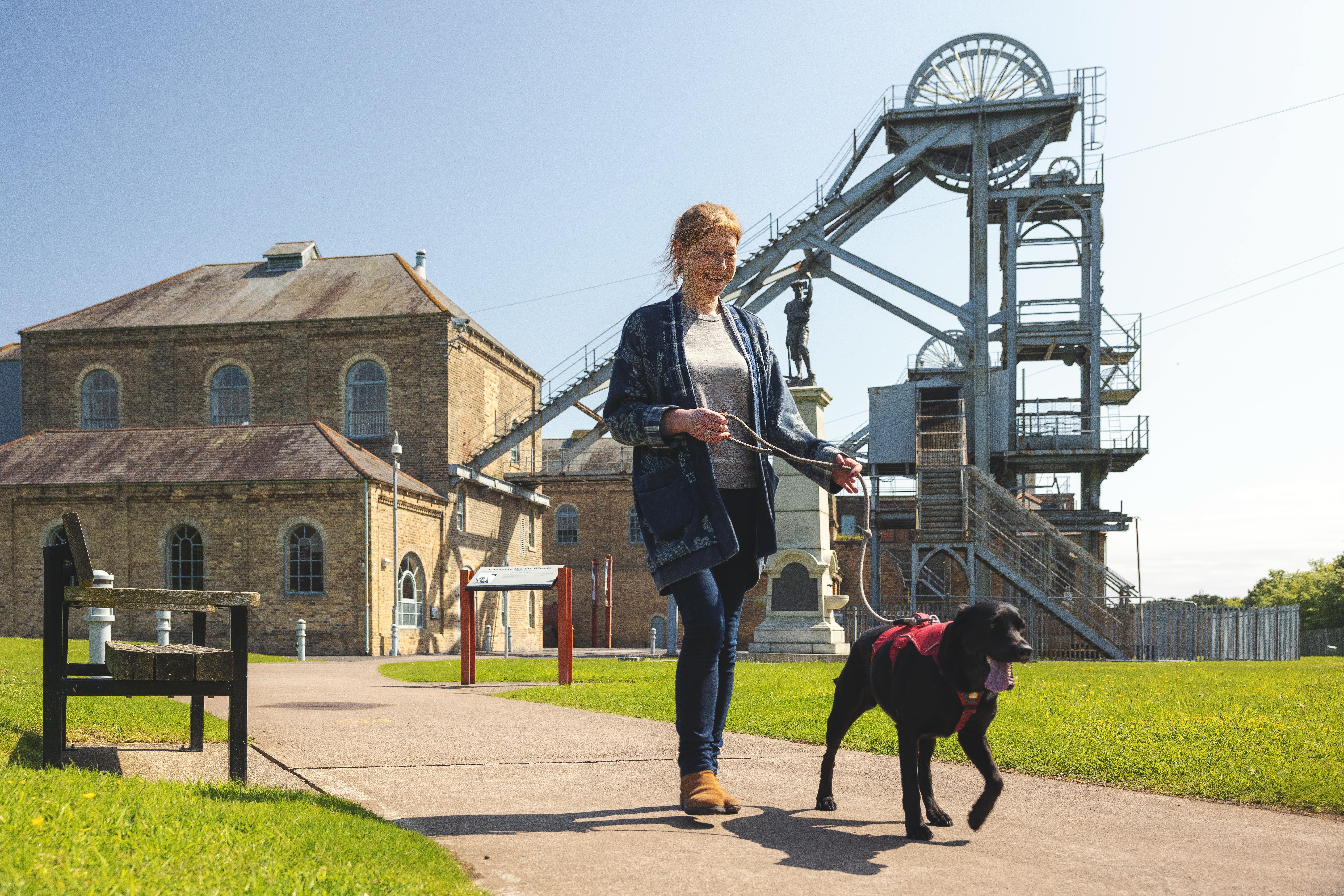 Woman walking through Woodhorn Museum outdoors with a dog