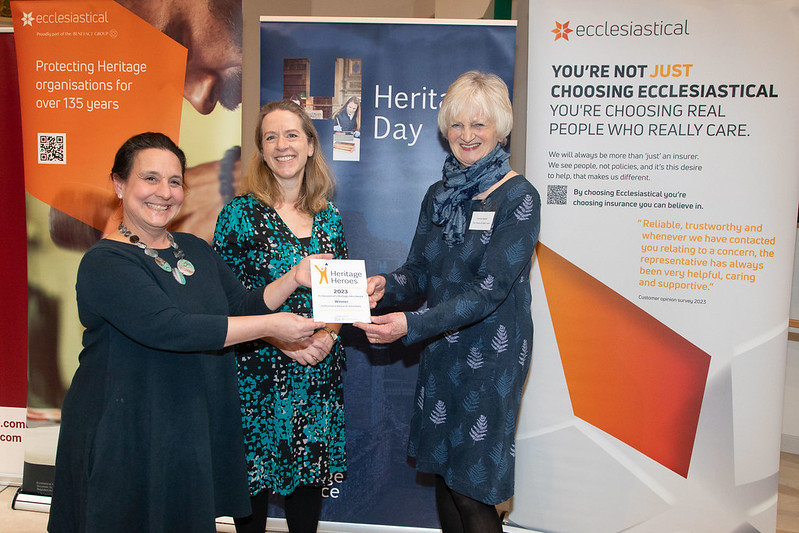 Group of three people holding the Heritage Heroes Award smiling to camera.