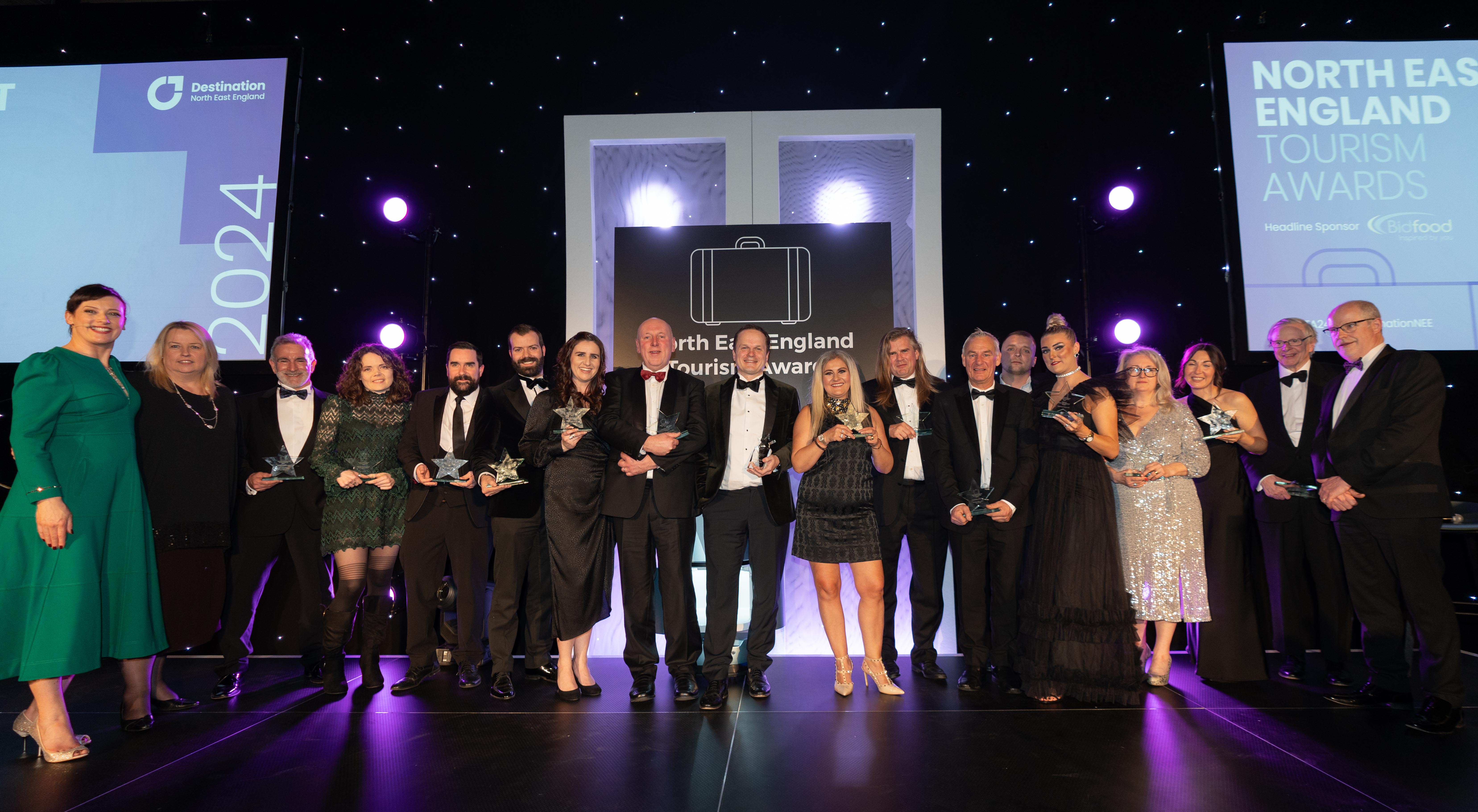 Group photo of Tourism Awards winners on stage together with their awards.