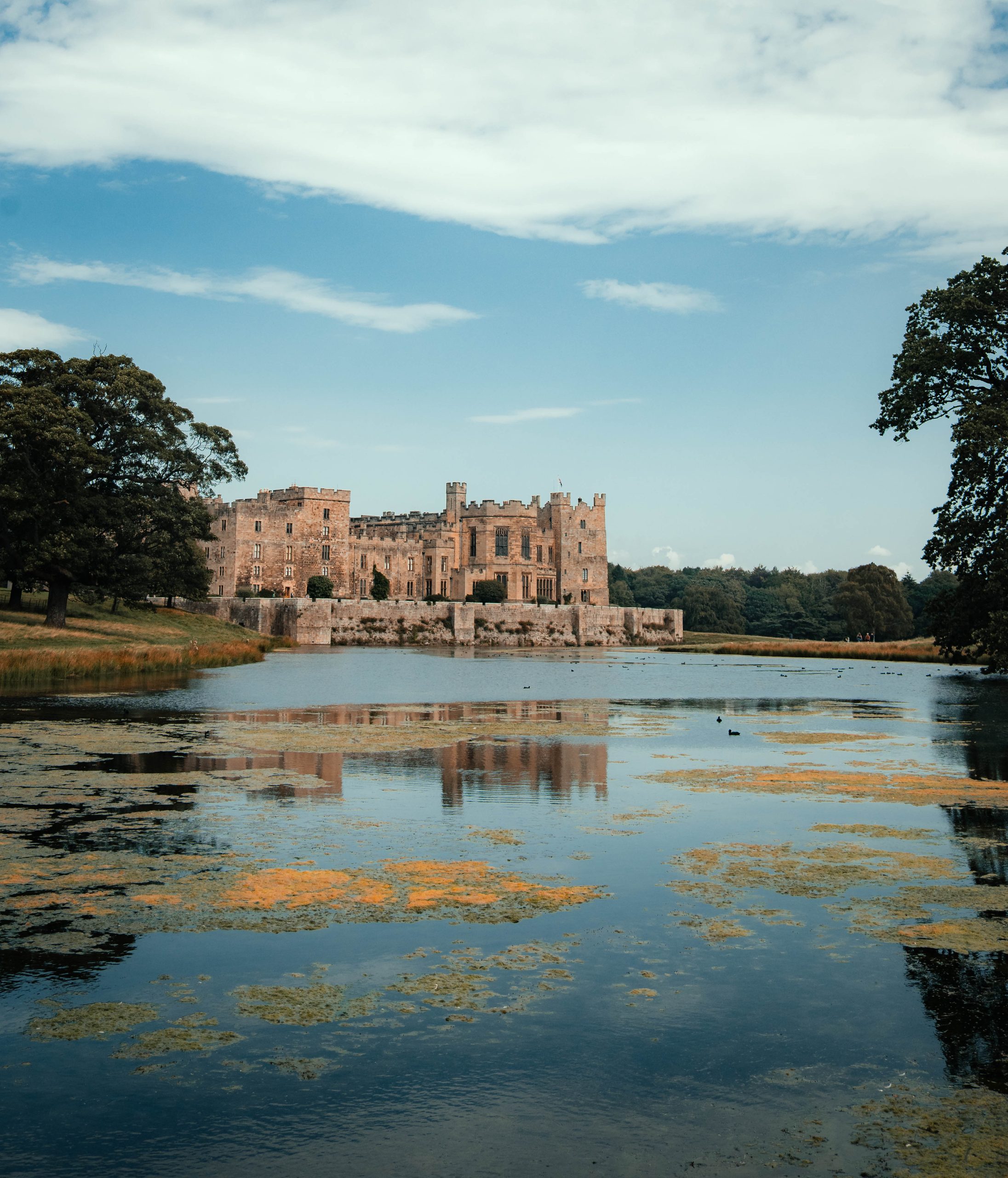 Image of Raby Castle surrounded by water and countryside at sunset