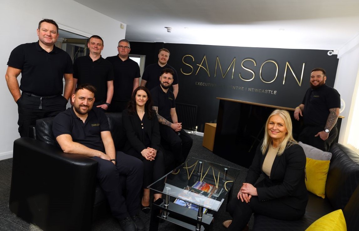 Group of people sat on sofas and stood in the new Samson Executive Lounge