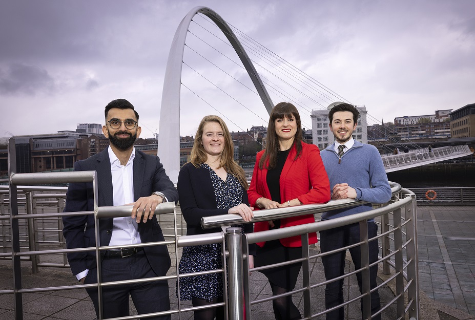 Group of four people stood next to the Millennium Bridge smiling to camera