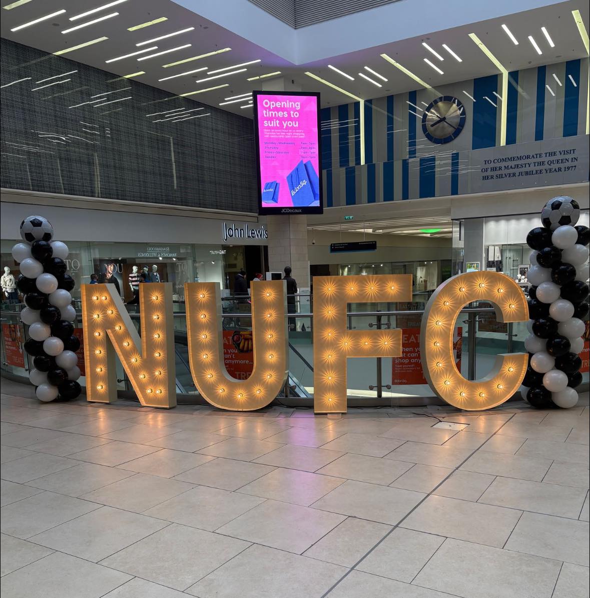 Light-up letters: NUFC inside Eldon Square shopping centre surrounded by black and white balloons.