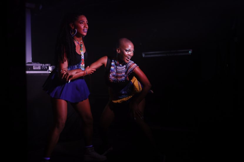 Two performers on stage with a spotlight on them as they look towards the audience.