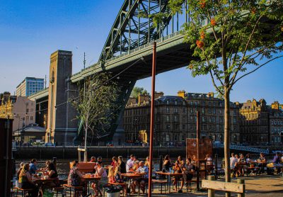 People enjoying the sunshine and food & drink on Gateshead Quayside sat underneath the Tyne Bridge.