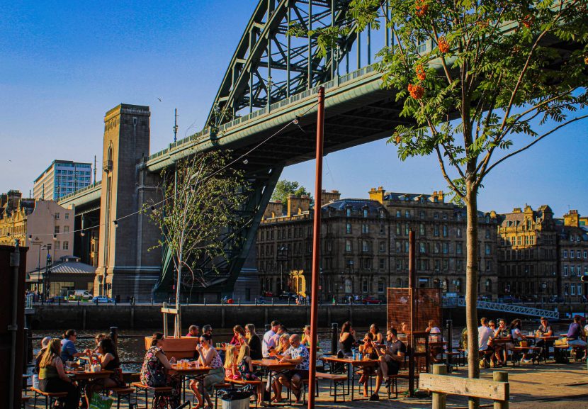 People enjoying the sunshine and food & drink on Gateshead Quayside sat underneath the Tyne Bridge.