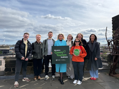 Group photo of NGI team on a rooftop in the city with two people holding Green Tourism banners.