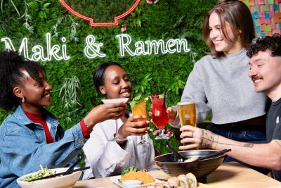 Group of people toasting their drinks at Maki & Ramen restaurant.