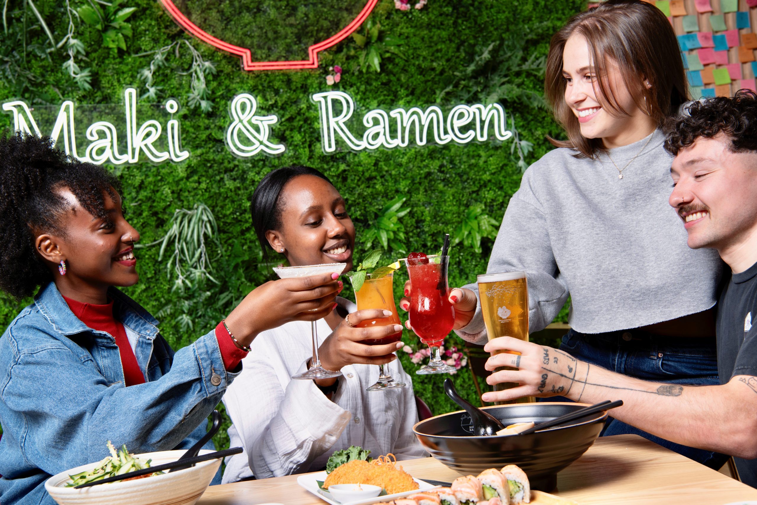 Group of people toasting their drinks at Maki & Ramen restaurant.