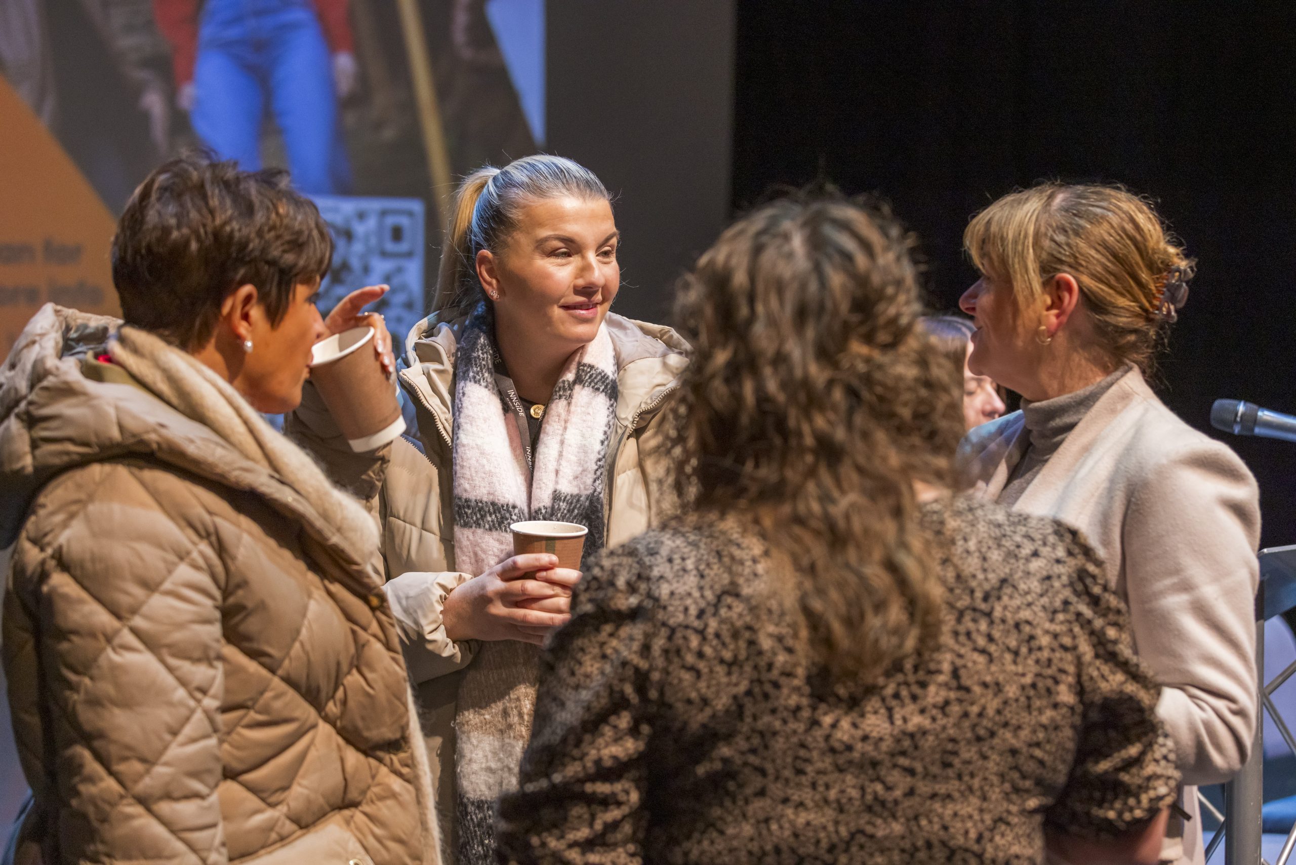 Group of four people networking holding coffee cups
