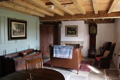 Inside Potters Cottage at Beamish Museum. The living room is Georgian in style with a small sofa and wooden dining table.