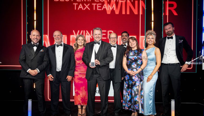 UNW tax team smiling on stage at award ceremony with their trophy