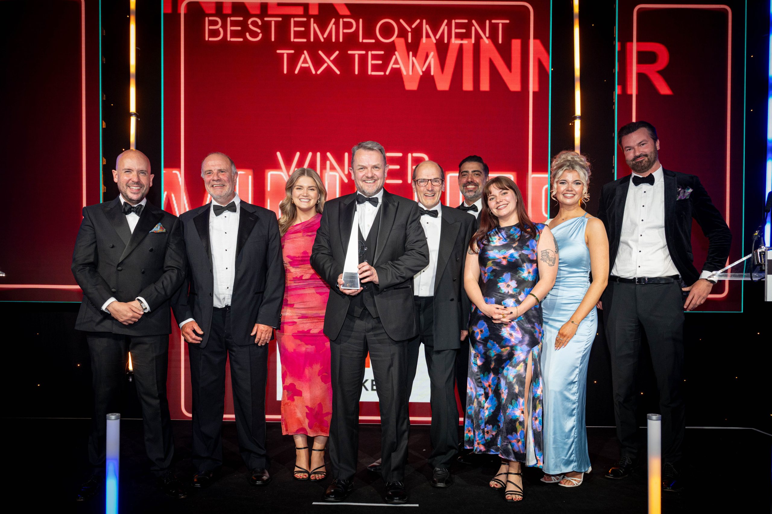 UNW tax team smiling on stage at award ceremony with their trophy