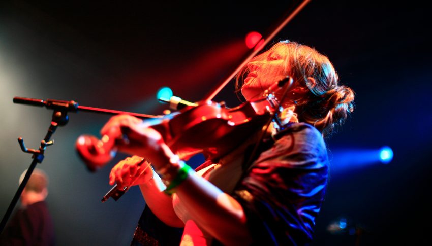 Violinist playing under stage lighting.