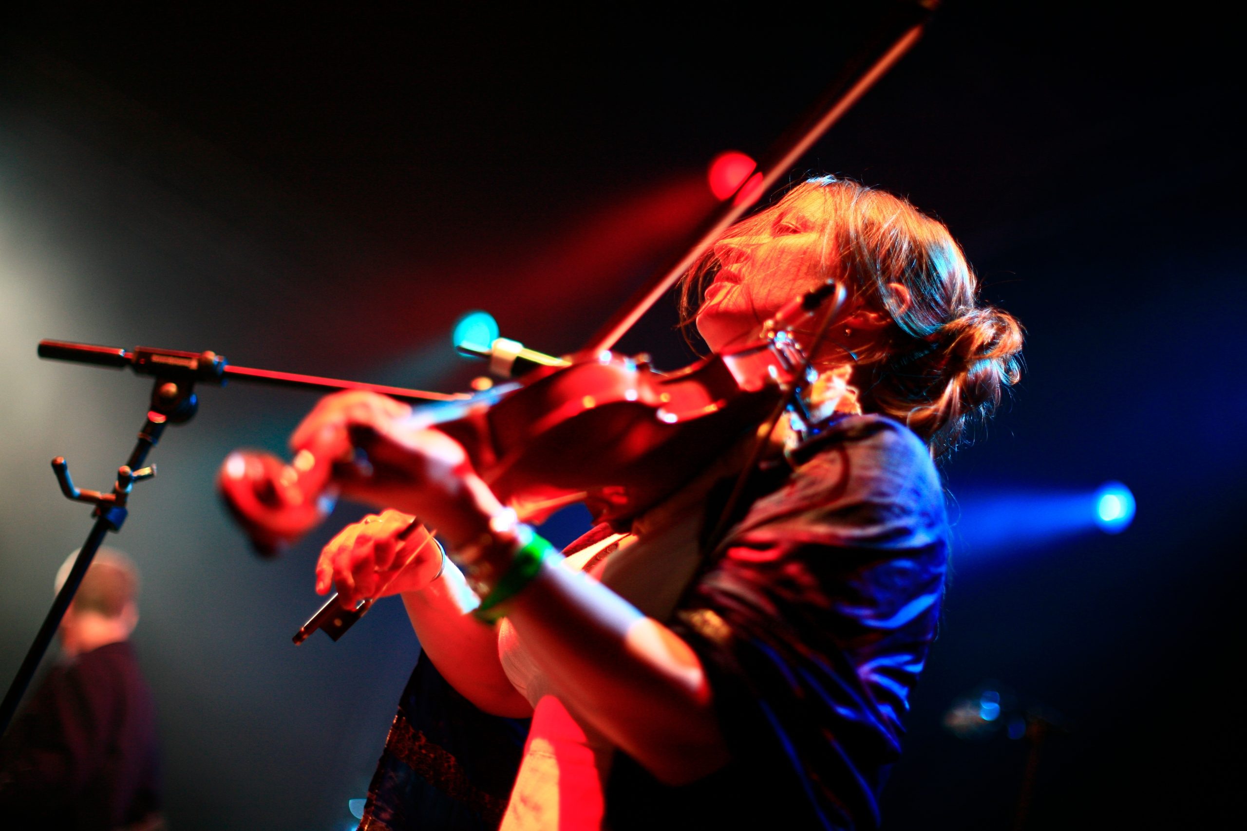 Violinist playing under stage lighting.