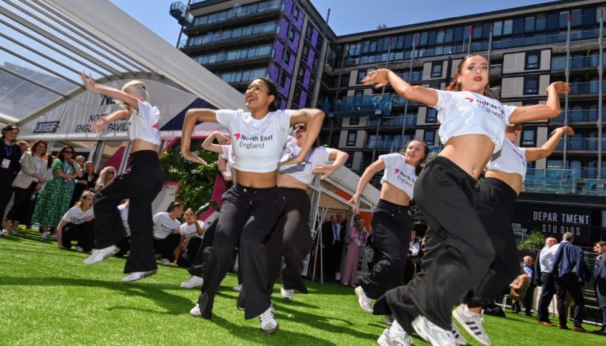 Group of young dancers mid-dance on grassy floor at UKREiiF
