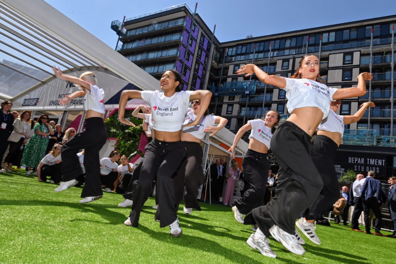 Group of young dancers mid-dance on grassy floor at UKREiiF