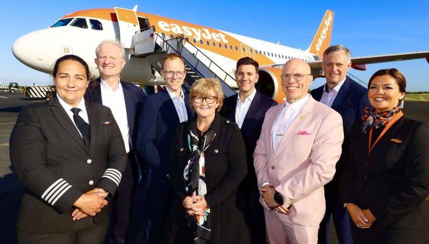 Group of easyJet staff members posing on the airfield in front of easyJet branded airplane