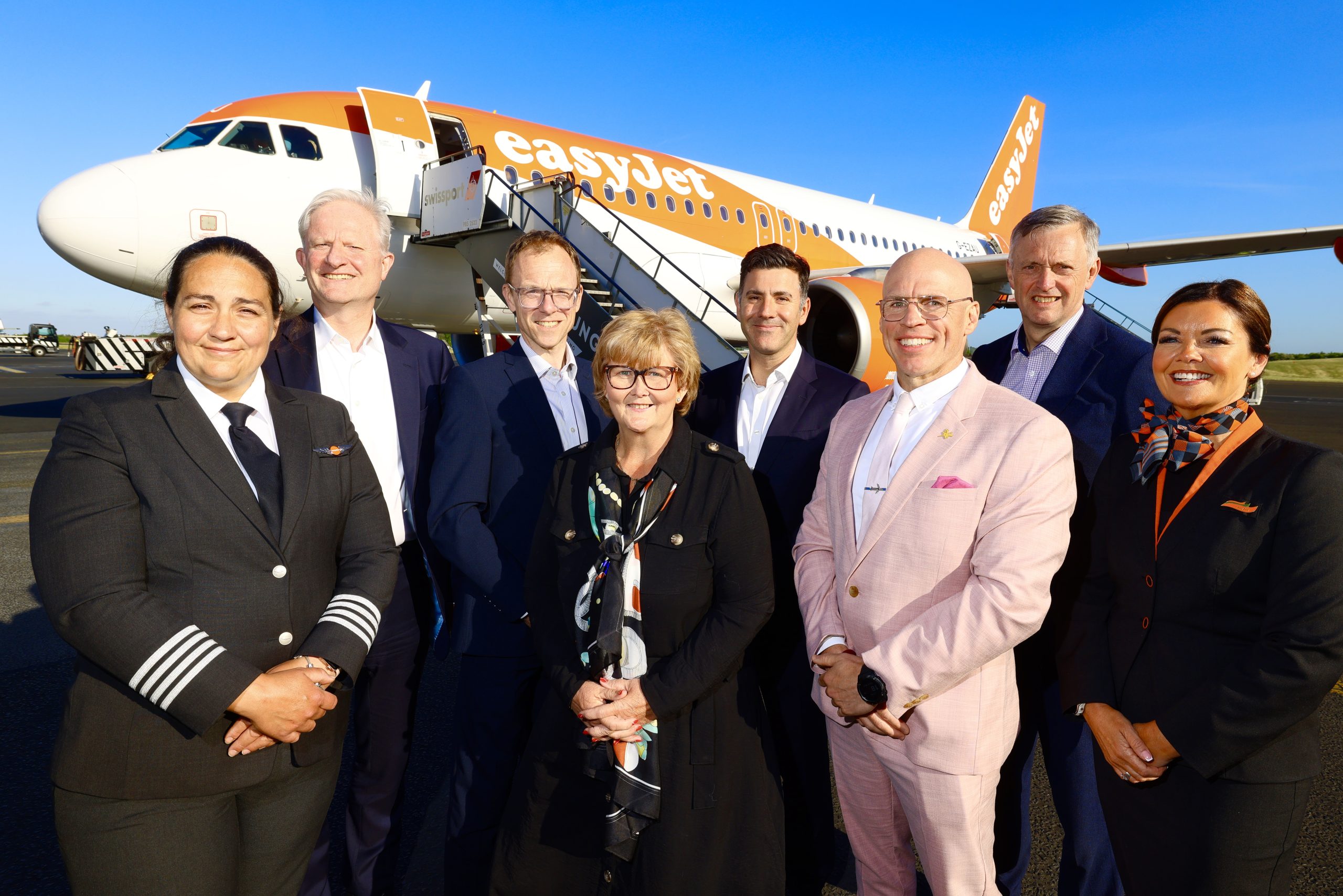 Group of easyJet staff members posing on the airfield in front of easyJet branded airplane