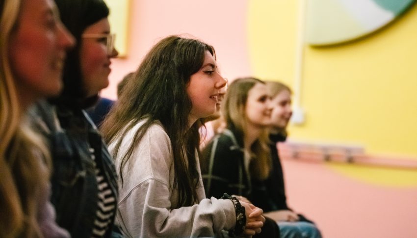 Young people sat in the audience looking to the right of the photo