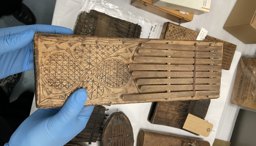Wooden block with etchings on it held by hands in blue gloves.