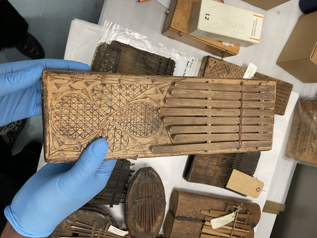 Wooden block with etchings on it held by hands in blue gloves.