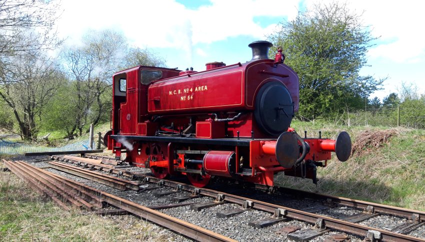 Red steam locomotive on a track in the countryside