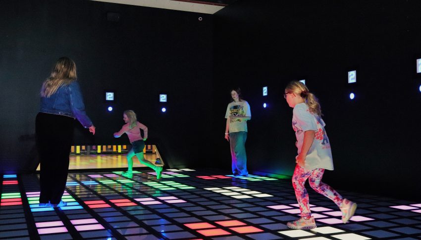 Group of adults and children playing on a light-up floor