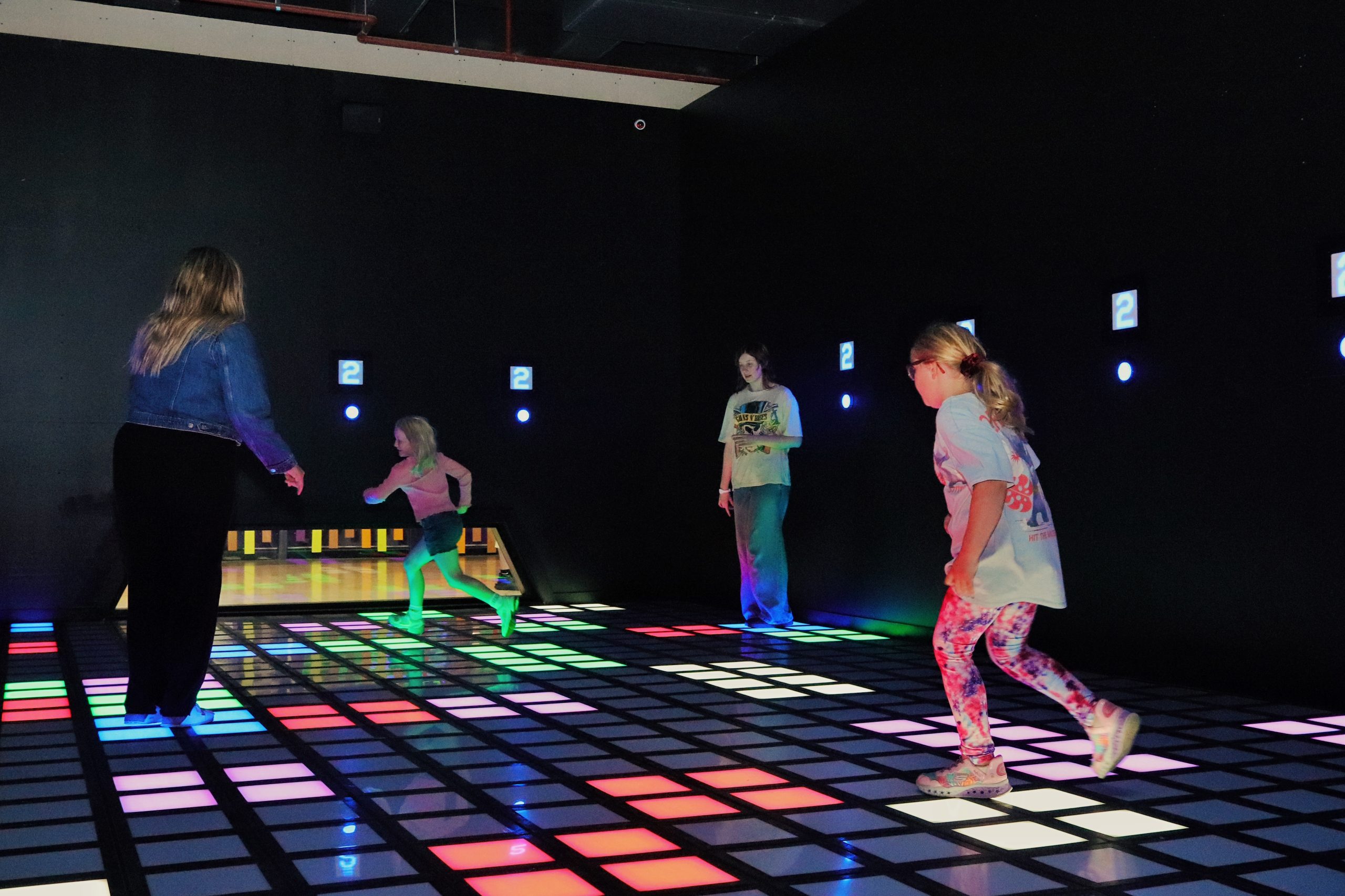 Group of adults and children playing on a light-up floor