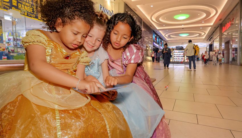 Three children in Disney princess dresses looking at a map in Eldon Square