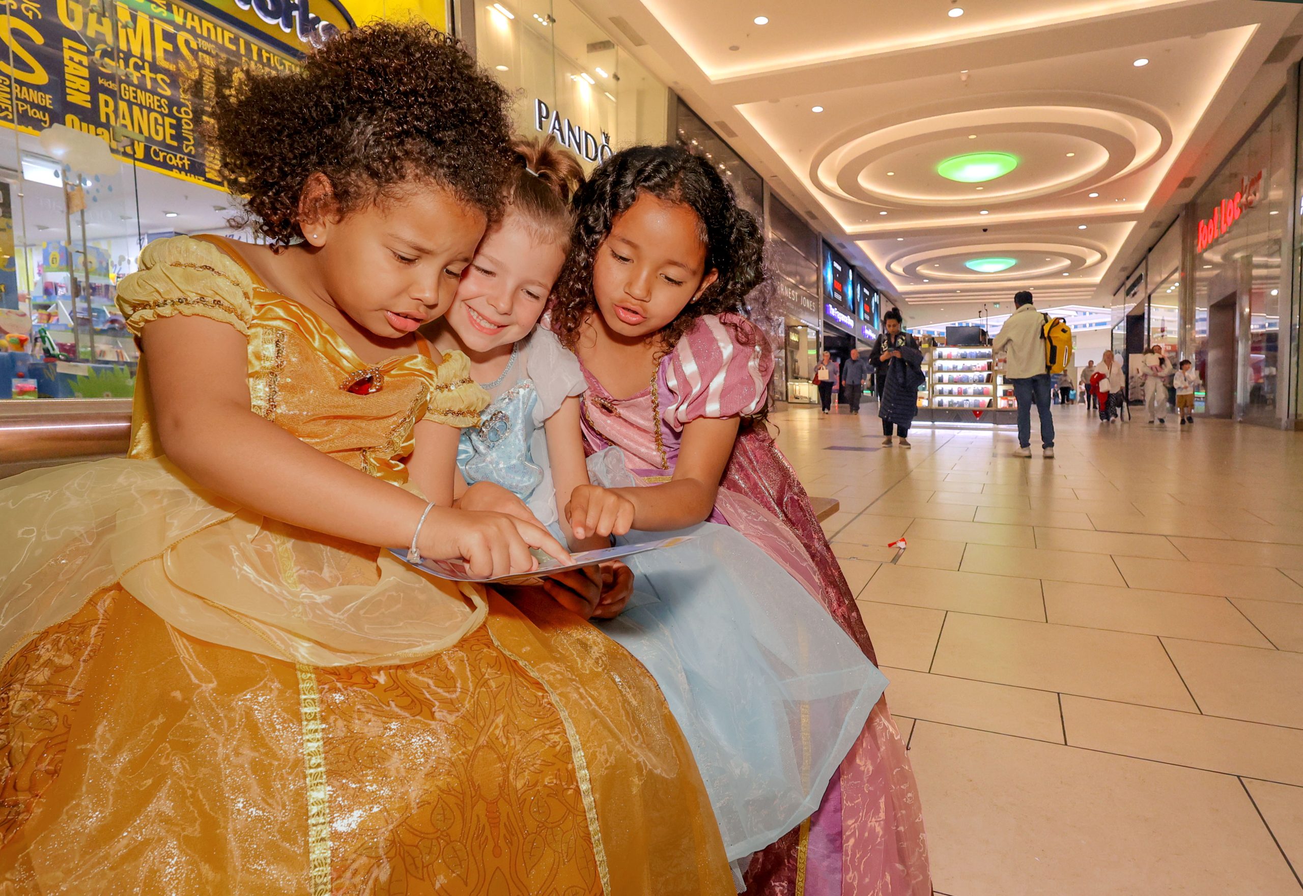 Three children in Disney princess dresses looking at a map in Eldon Square