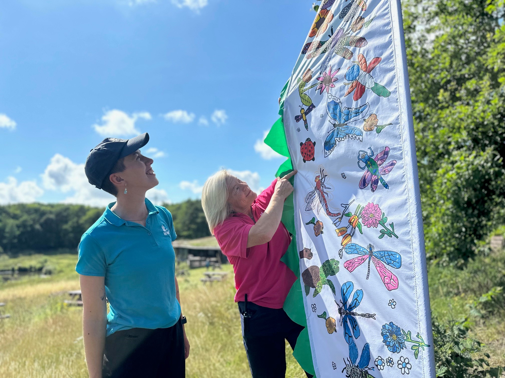 Two people lookinhg at an arty flag at WWT in the bright sunshine.