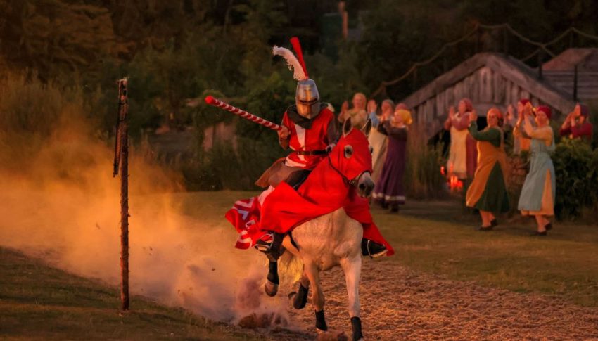 Person in medieval knight costume riding a horse at night with a joust in hand