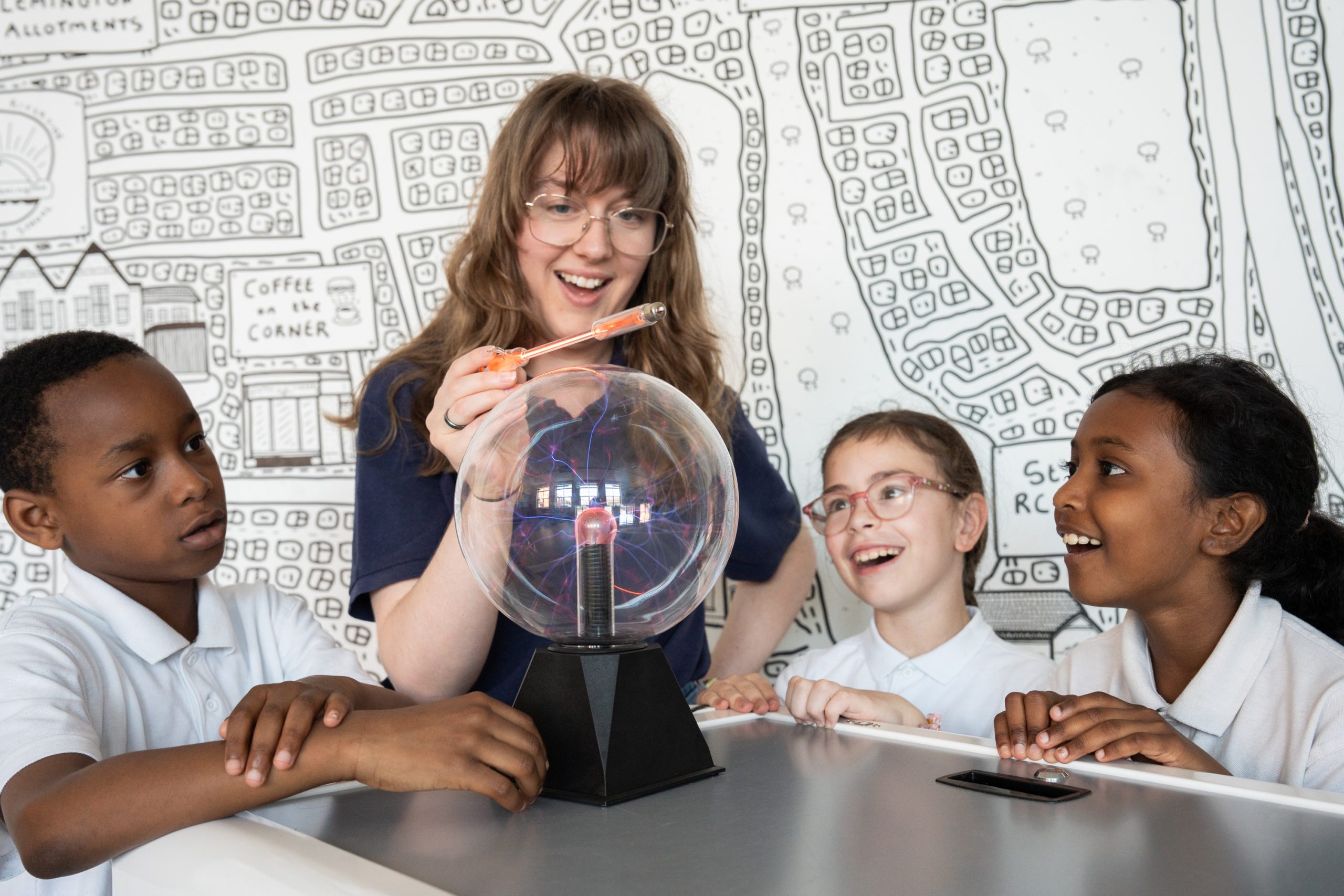 Adult working on a science experiment with three children looking on in wonder.