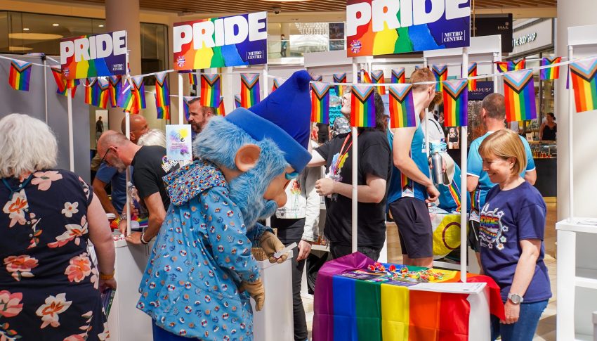 Pride stalls in Metrocentre with blue Metro Gnome getting involved
