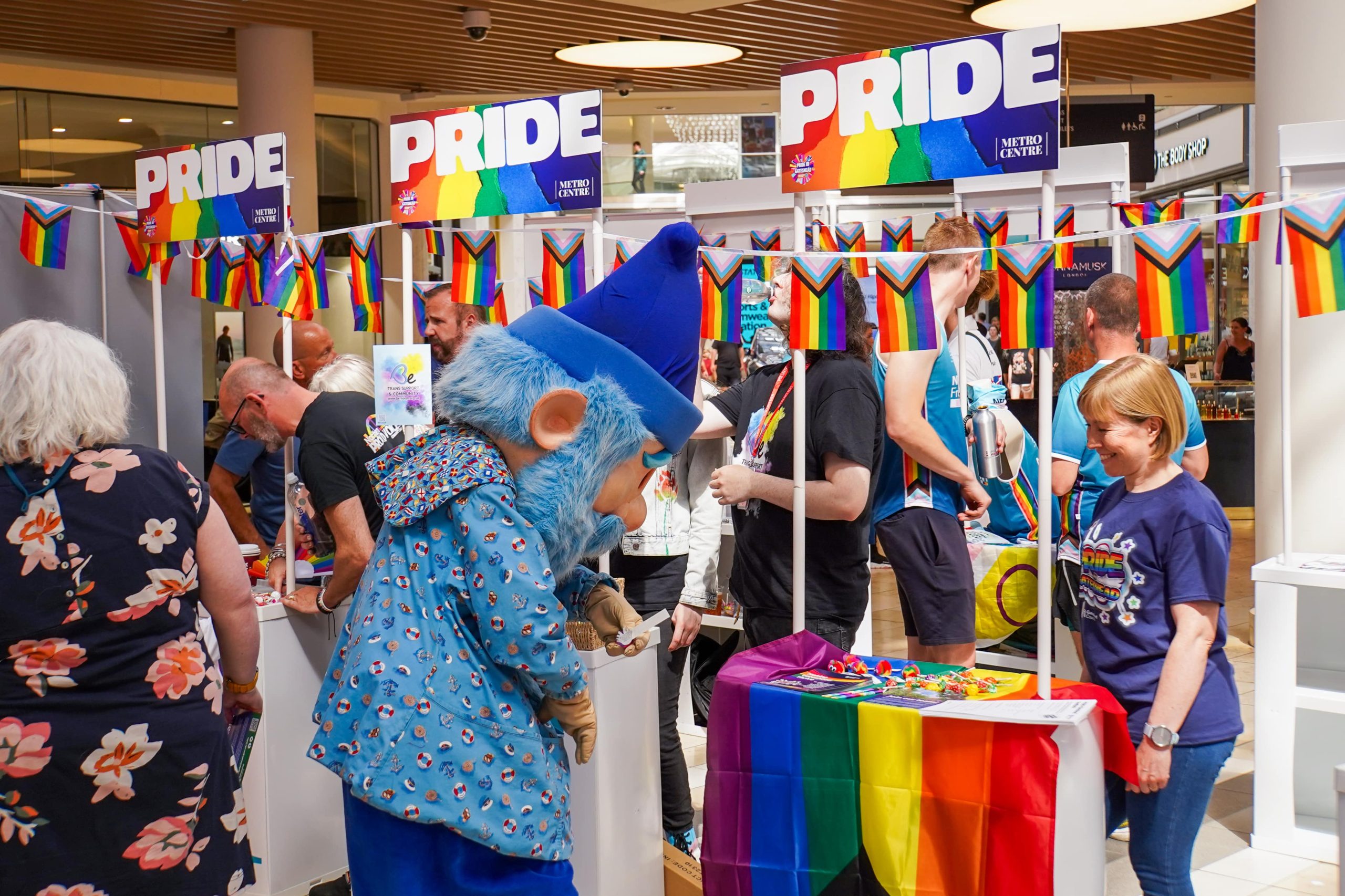 Pride stalls in Metrocentre with blue Metro Gnome getting involved