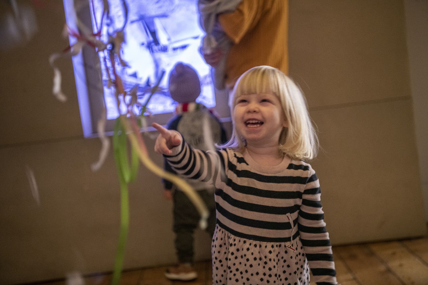 Child laughing as they look and point at a sculpture.